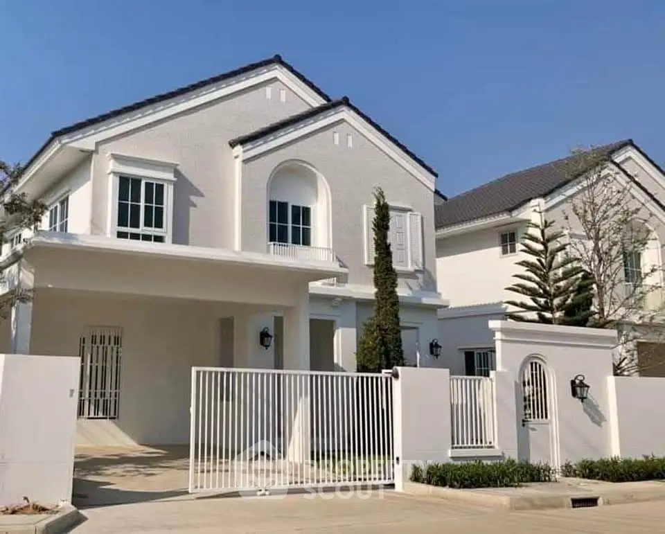 Elegant two-story white house with gated entrance and manicured landscaping under clear blue sky.