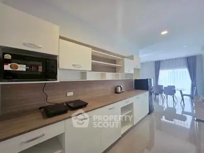 Modern kitchen with sleek cabinets and dining area, featuring microwave and induction cooktop.