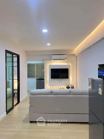 Modern living room with sleek design and ambient lighting, featuring a cozy sofa and wall-mounted TV.