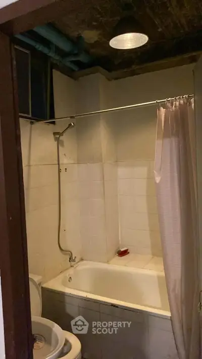 Cozy bathroom with bathtub and shower in a compact space, ideal for efficient living.