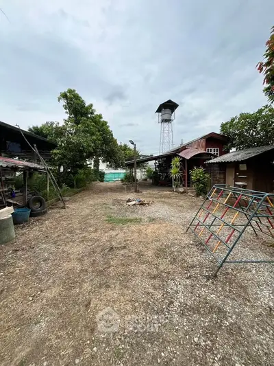 Spacious rustic outdoor area with a water tower and surrounding greenery, ideal for development or leisure.