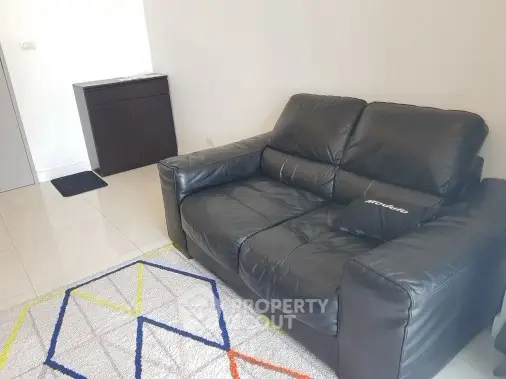 Cozy living room with black leather sofa and modern geometric rug