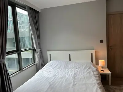 Modern bedroom with large window and minimalist decor in urban apartment.