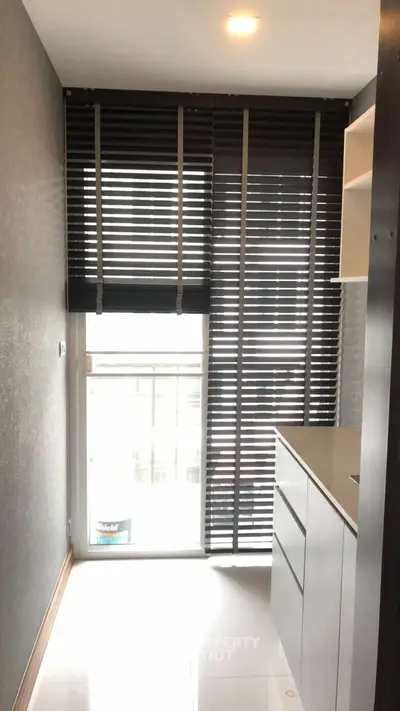 Modern kitchen with sleek cabinetry and large window blinds