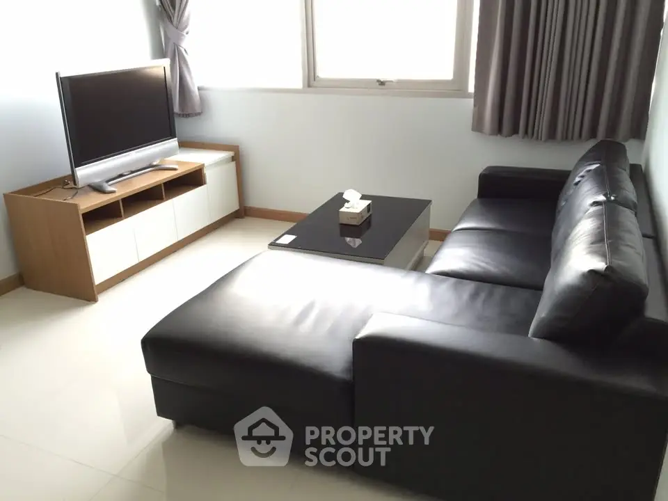 Modern living room with sleek black leather sofa and flat-screen TV