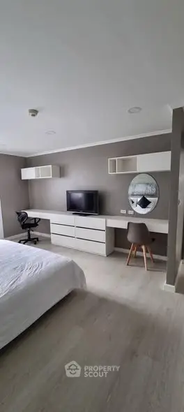 Modern bedroom with sleek furniture and workspace, ideal for comfort and productivity.
