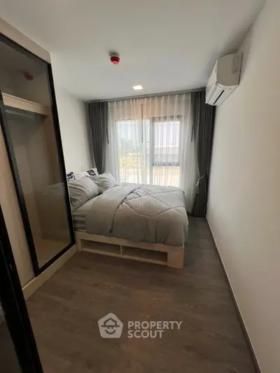 Cozy bedroom with modern decor and large window offering natural light.