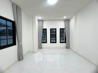 Spacious empty room with large windows and elegant curtains, perfect for customization.
