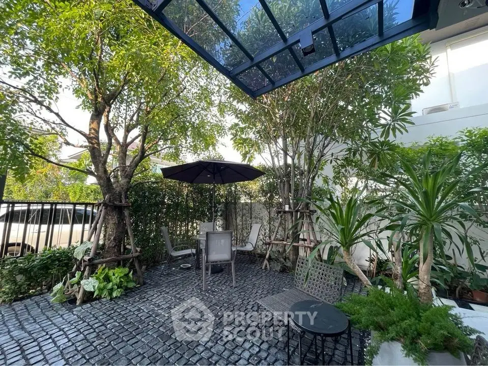 Charming garden patio with lush greenery and modern outdoor seating.