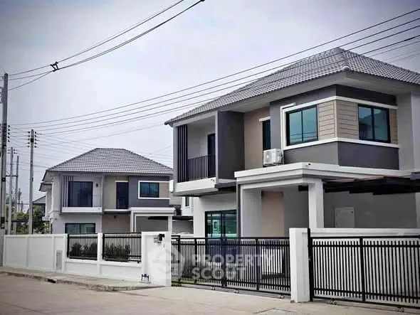 Modern two-story houses with sleek design and gated entrance in suburban neighborhood.