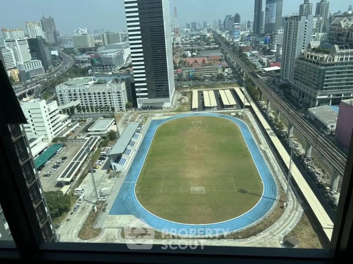 Stunning cityscape view from high-rise building overlooking a sports field and urban skyline.