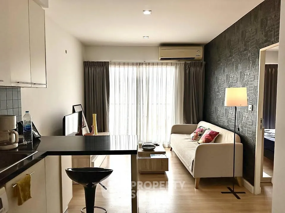 Modern living room with stylish decor and natural light, featuring a cozy sofa and open kitchen layout.
