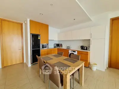 Modern kitchen with wooden cabinets and dining area in open layout apartment.
