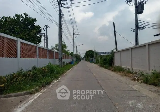 Quiet suburban street with surrounding walls and greenery, ideal for peaceful living.