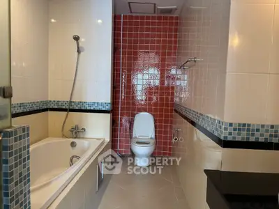 Modern bathroom with bathtub and red accent wall tiles