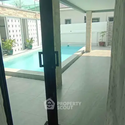 Luxurious poolside view from modern home with sleek design and spacious patio area.