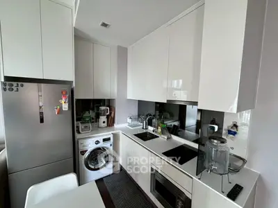 Modern kitchen with sleek appliances and compact design, featuring a washing machine and built-in oven.