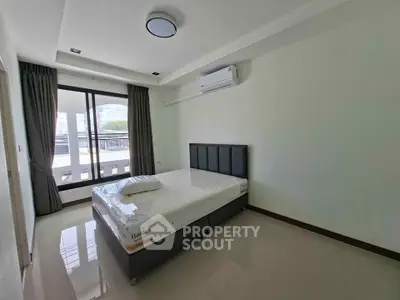 Spacious bedroom with modern design and large window offering natural light.