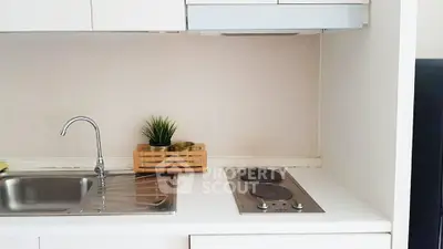 Modern compact kitchen with electric stove and sleek white cabinetry