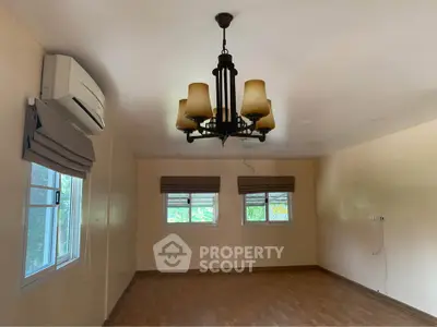 Spacious empty room with elegant chandelier and air conditioning, perfect for customization.