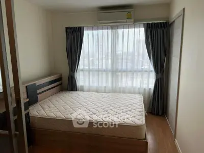 Cozy bedroom with large window and modern furnishings in urban apartment.