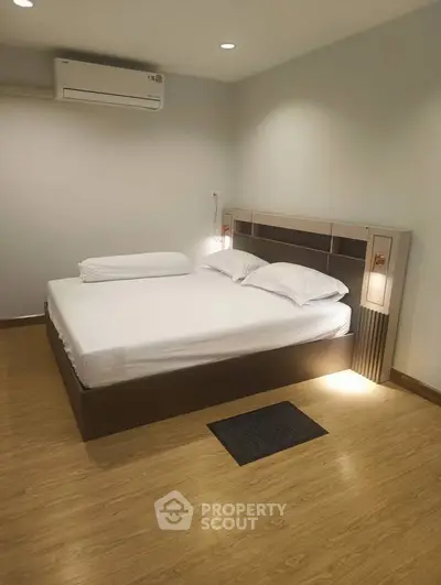 Modern bedroom with sleek design and wooden flooring, featuring a comfortable bed and ambient lighting.