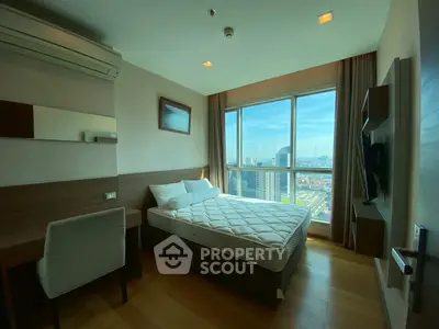 Modern bedroom with city view and natural light, featuring a comfortable bed and stylish decor.
