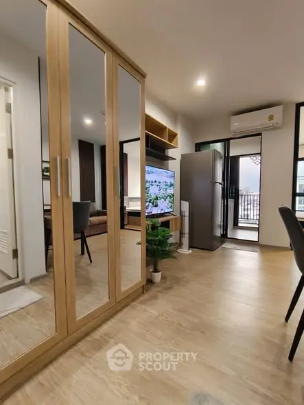 Modern apartment interior with mirrored wardrobe, open living area, and balcony view.