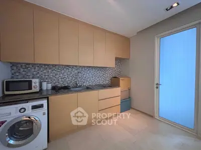 Modern kitchen with sleek cabinetry, washing machine, and stylish backsplash in a contemporary home.