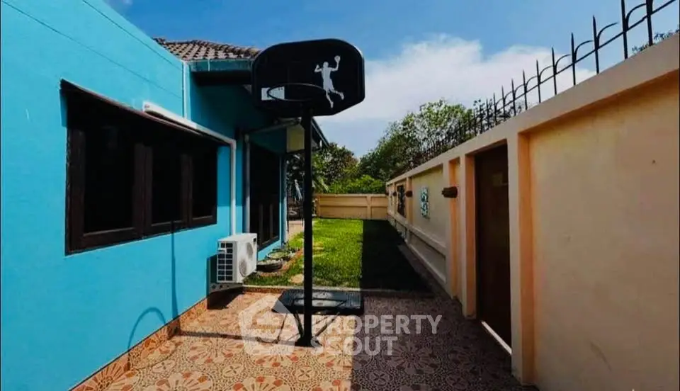 Charming backyard with basketball hoop and vibrant blue exterior wall, perfect for outdoor activities.