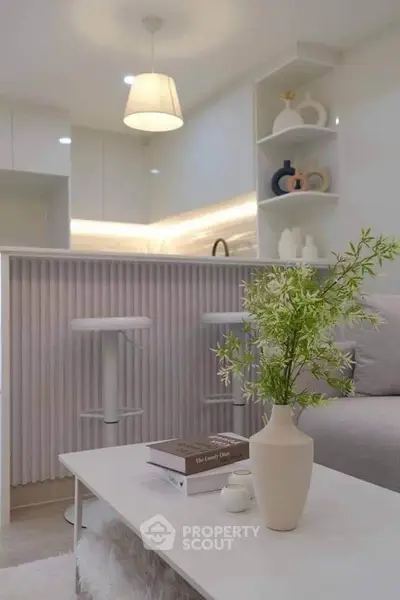 Modern living room with stylish decor and open kitchen layout, featuring elegant lighting and cozy seating.