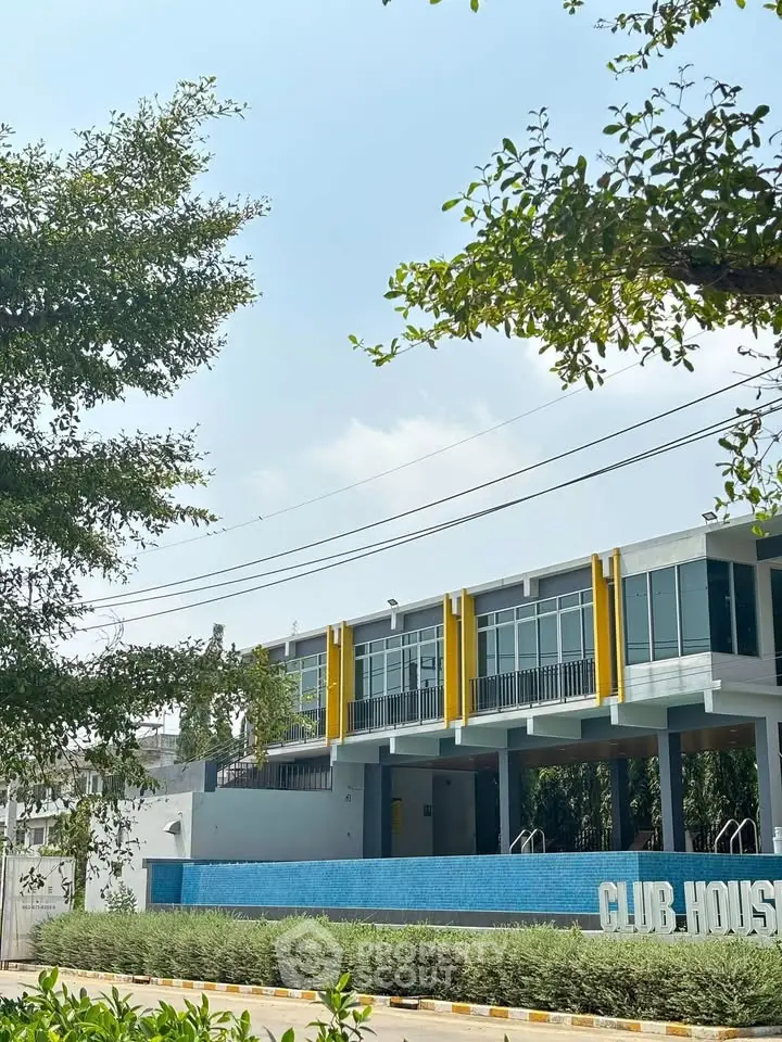 Modern clubhouse exterior with sleek design and lush greenery, perfect for luxury living.