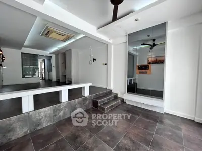Spacious modern interior with sleek tiled flooring and ceiling fan, ideal for versatile living or office space.