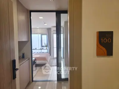 Modern apartment entrance leading to a cozy bedroom with natural light.