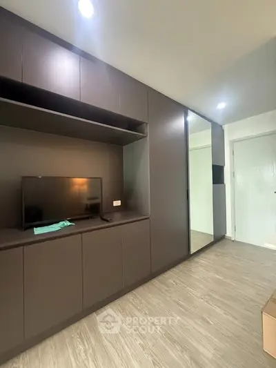 Modern living room with sleek built-in cabinets and TV, showcasing minimalist design and ample storage space.