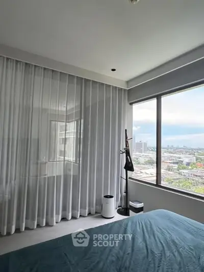 Modern bedroom with large window offering stunning city view and elegant decor.