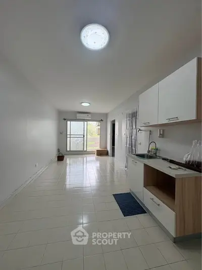 Spacious open-plan living area with modern kitchen and large window for natural light.