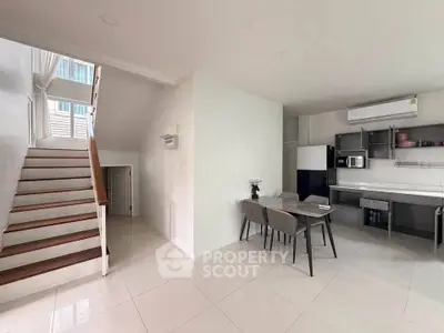 Modern open-plan kitchen and dining area with sleek design and staircase