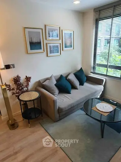 Chic living room with modern decor, cozy sofa, and large window offering natural light and greenery view.