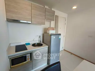 Modern compact kitchen with sleek cabinetry and appliances in a stylish apartment.