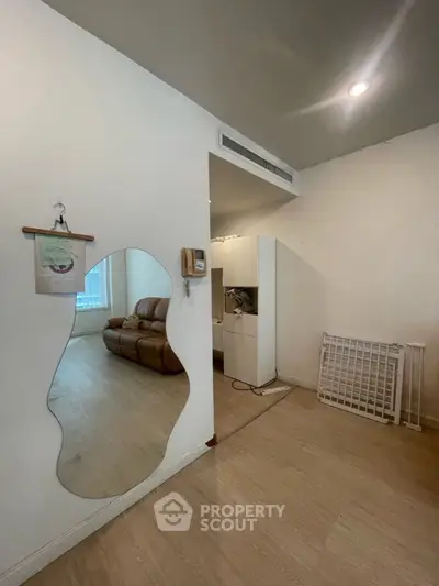 Spacious living area with modern decor and unique wall mirror