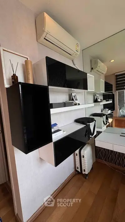 Modern study room with sleek black and white shelving, air conditioning, and wooden flooring.