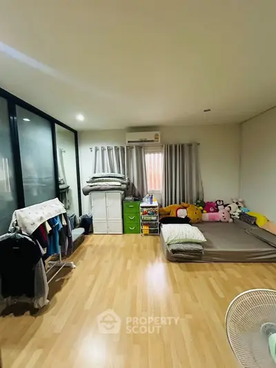 Spacious bedroom with wooden flooring and cozy decor