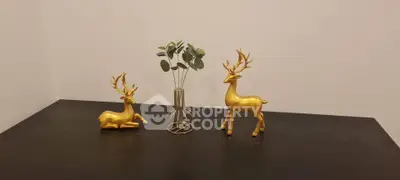 Elegant tabletop decor with golden deer figurines and vase in modern interior.