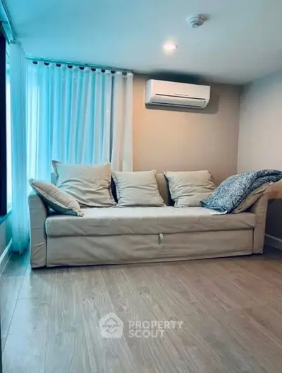 Cozy living room with modern sofa and air conditioning, perfect for relaxation.