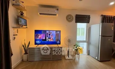 Modern living room with stylish decor, featuring a TV, air conditioning, and a large fridge.