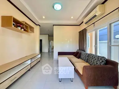 Spacious living room with modern sofa and air conditioning, featuring elegant shelving and natural light.