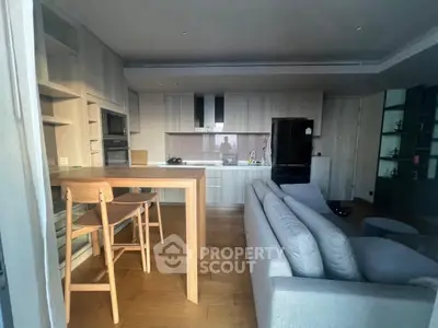 Modern open-plan living room and kitchen with sleek design and wooden flooring.