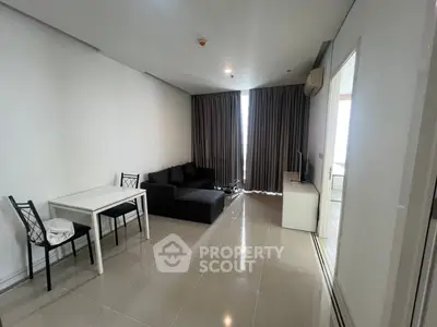 Modern living room with sleek black sofa and dining area in contemporary apartment.