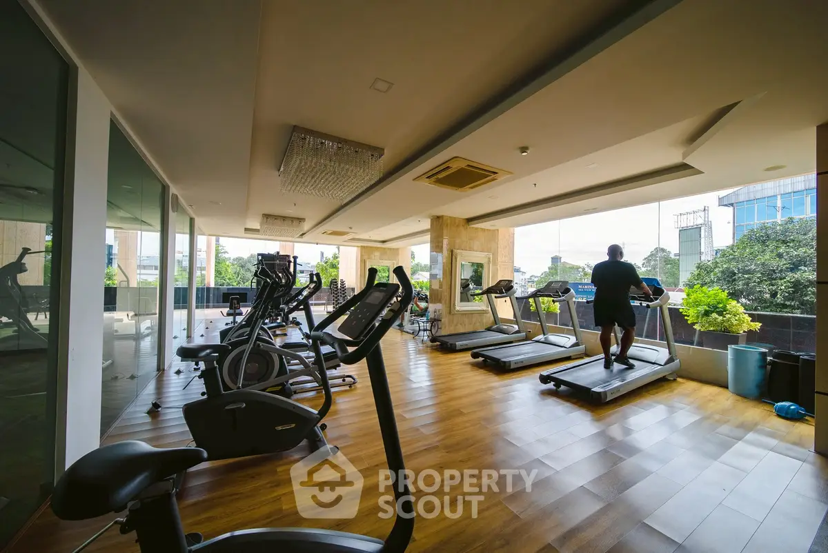 Spacious gym with modern equipment and large windows offering a scenic view.